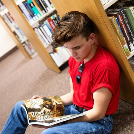 Person, siddende på gulvet, læser i bog