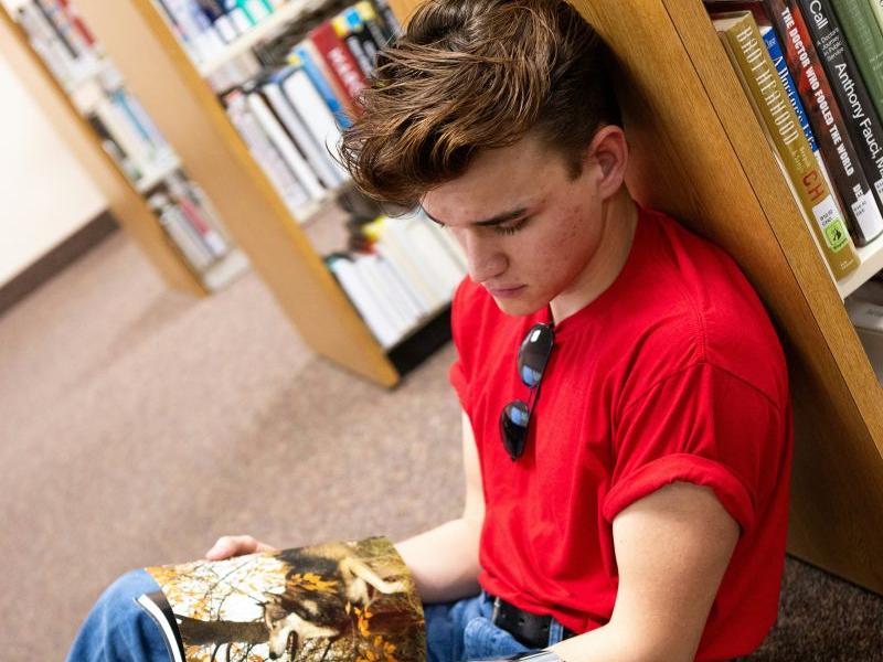 Person, siddende på gulvet, læser i bog